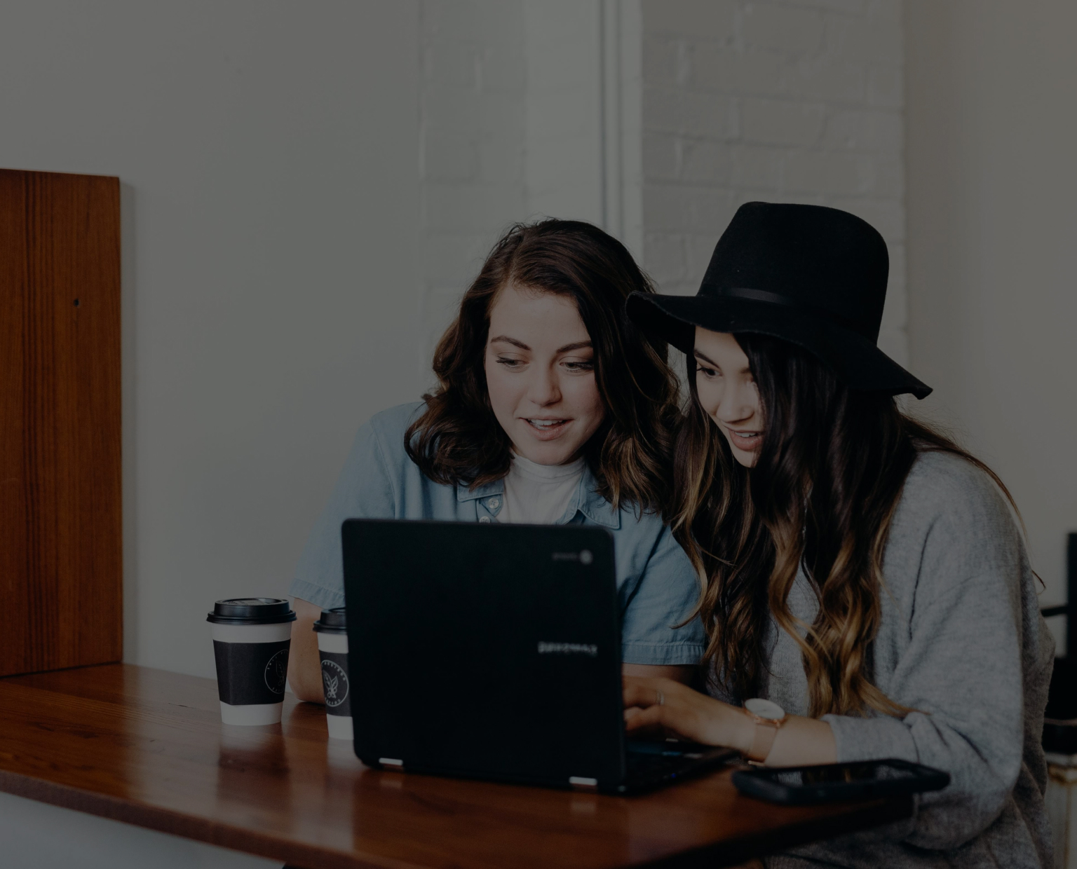 Duas mulheres olham para um laptop.